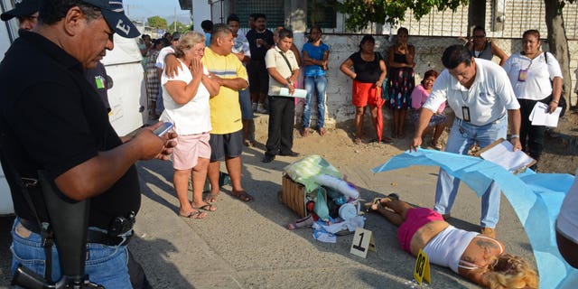 A forensic worker covers the body of a woman who was shot dead by assailants, whose daughter was also killed, while she was selling coffee on a street corner in Acapulco, Mexico, Tuesday, April 9, 2013. Violence, kidnappings and extortions carried out by drug cartels continue to plague this Pacific resort city which has witnessed a large increase in violent crimes during the past years. (AP Photo/Bernandino Hernandez)