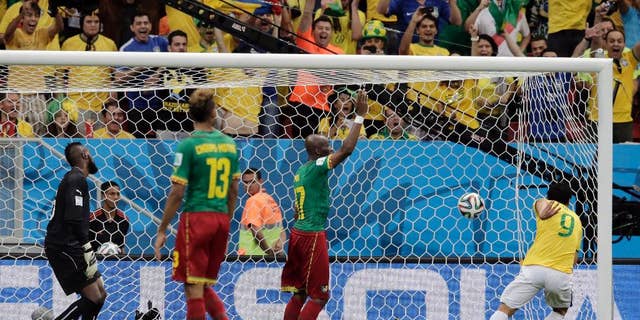 Spectators cheer as Brazil's Fred (9) scores his side's third goal against Cameroon's goalkeeper Charles Itandje during the group A World Cup soccer match between Cameroon and Brazil at the Estadio Nacional in Brasilia, Brazil, Monday, June 23, 2014. (AP Photo/Bernat Armangue)