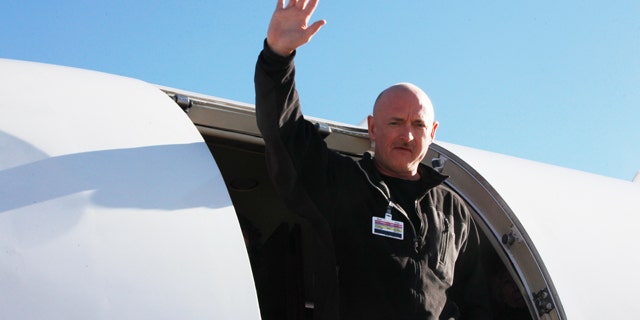 Astronaut Mark Kelly waves after his Rep. Giffords was loaded onto an airplane in Tucson, Ariz., as she is transferred to a rehabilitation center in Houston, Friday, Jan. 21, 2011.
