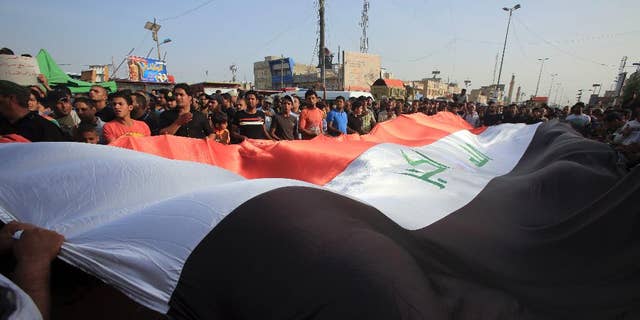 Protesters wave a giant Iraq flag as they chant anti-government slogans during a demonstration against the security forces' failure to protect them from car bombs Thursday.