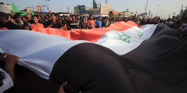 Protesters wave a giant Iraq flag as they chant anti-government slogans during a demonstration against the security forces' failure to protect them from car bombs Thursday.