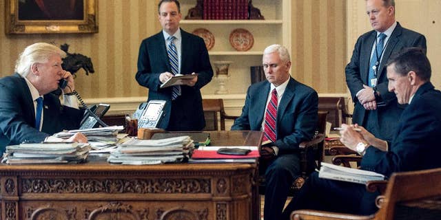 FILE - In this Jan. 28, 2017 file photo, President Donald Trump accompanied by, from second from left, Chief of Staff Reince Priebus, Vice President Mike Pence, White House press secretary Sean Spicer and then-National Security Adviser Michael Flynn speaks on the phone with Russian President Vladimir Putin, in the Oval Office at the White House in Washington.