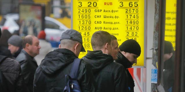 People stand in line at a currency exchange bureau in Kiev, Ukraine, Thursday, Nov. 13, 2014.  Ukraine's hryvnia plunged to UAH 15.56/USD on Nov. 13, a 14% decline since Nov. 5, when the National Bank of Ukraine reduced its interventions at the ForEx and allowed further weakening. Ukraine's national currency has already lost nearly 47% of its value this year, falling from UAH 8.1/USD.  (AP Photo/Efrem Lukatsky)