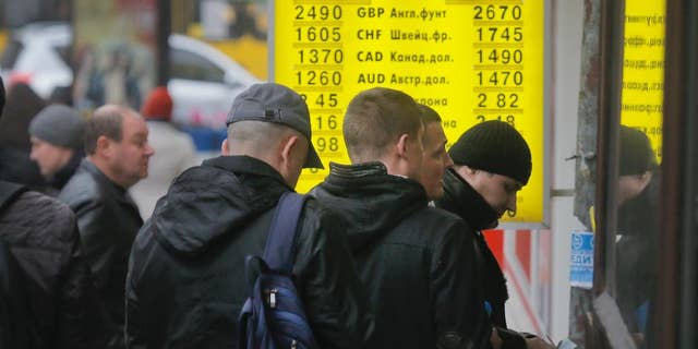 People stand in line at a currency exchange bureau in Kiev, Ukraine, Thursday, Nov. 13, 2014. Ukraine's hryvnia plunged to UAH 15.56/USD on Nov. 13, a 14% decline since Nov. 5, when the National Bank of Ukraine reduced its interventions at the ForEx and allowed further weakening. Ukraine's national currency has already lost nearly 47% of its value this year, falling from UAH 8.1/USD. (AP Photo/Efrem Lukatsky)