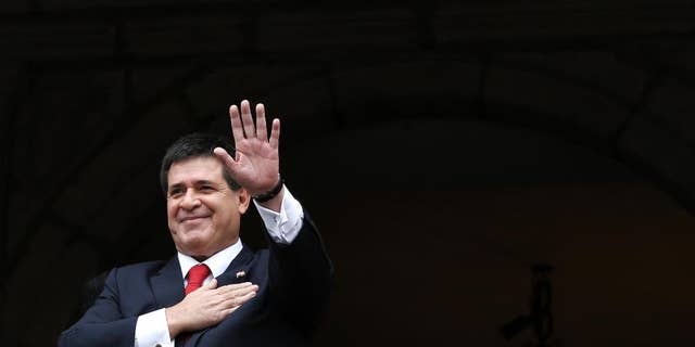 FILE - In this Nov. 21, 2014 file photo, Paraguay's President Horacio Cartes waves from a government palace balcony, in Quito, Ecuador. President Cartes said Monday, April 17, 2017, that he will not be a candidate in the 2018 election even if Congress approves a constitutional amendment to allow a second term. (AP Photo/Dolores Ochoa, File)