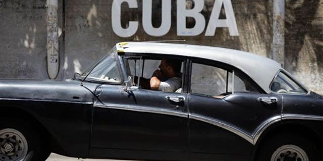 A man drives his taxi past a Cultural Center with the word "Cuba" on it, in Havana, Cuba, Tuesday, April 14, 2015.