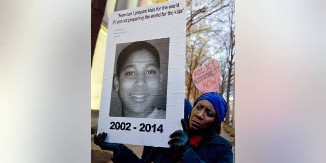 FILE - In this Dec. 1, 2014, file photo, Tomiko Shine holds up a picture of Tamir Rice, the 12 year old boy fatally shot by a rookie police officer in Cleveland, Ohio, on Nov. 22, during a protest in Washington, D.C. Cleveland.com reported newly public recorded police interviews with Officers Frank Garmback and Timothy Loehmann were done within days of the November 2014 death of Rice, who'd been playing with a pellet gun. (AP Photo/Jose Luis Magana, File)