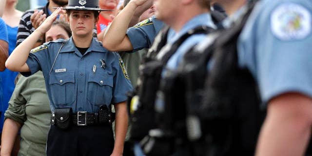 A police explorer salutes as police officials follow Fox Lake Police Lt. Charles Joseph Gliniewicz's family after a vigil at Lakefront Park.