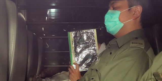 Malaysian citizen Khaw Kim Sun, 53, center, covered face, is escorted in a prison bus leaving the court after being sentenced to life in prison in Hong Kong.