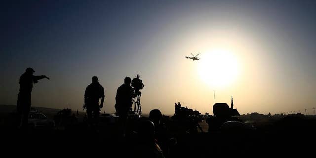 An Iraqi military helicopter flies over the frontline near Bartella, Iraq on Thursday, Oct. 20, 2016. Iraqi special forces charged into the Mosul battle Thursday with a pre-dawn advance on the nearby town held by the Islamic State group, a key part of a multi-pronged assault on eastern approaches to the besieged city. (AP Photo/Bram Janssen)