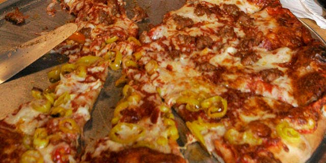 ** FILE ** Republican presidential hopeful, former New York City Mayor Rudy Giuliani eats pizza during a visit to the Sunseri Italian Market in the Strip District of Pittsburgh in this June 27, 2007 file photo. When AP asked the presidential candidates to name a food they shun, his pick was liver. (AP Photo/Gene J. Puskar. File)