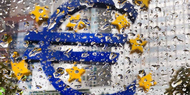 The Euro sculpture in front of the old European Central Bank is photographed behind rain drops on a window in Frankfurt, Germany, Tuesday, Oct. 18, 2016. The governing council of the ECB will meet on Thursday. (AP Photo/Michael Probst)
