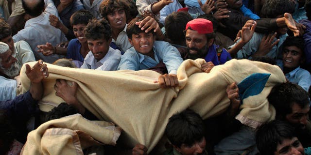Pakistanis displaced by flooding fight for blankets during an aid distribution by the Pakistani Air Force at a temporary camp set up for residents who had to flee their homes in Sukkar, Sindh Province, southern Pakistan, Thursday, Aug. 19, 2010.