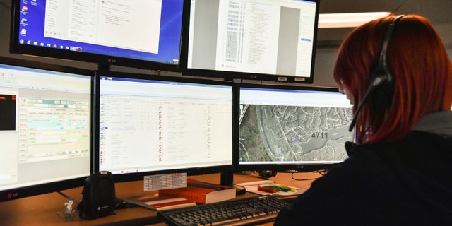 A 911 dispatcher in Roswell, Ga., works with a variety of screens while handling a call, March 15, 2018.