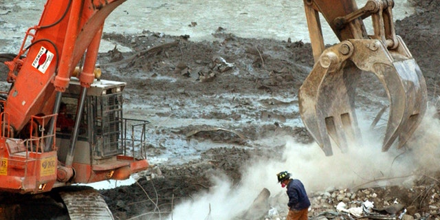 In this Jan. 8, 2001 file photo, a rescue worker wearing a dust mask, peers through a cloud of dust created by an excavator at the World Trade Center site in New York. The New York governor's pardon of Carlos Cardona for a 1990 drug conviction is the latest example of politicians trying to rescue individuals from their immigration problems. Cardona worked on the World Trade Center recovery operation after the 2001 terrorist attacks. (AP Photo/Mark Lennihan, File)