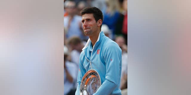 Serbia's Novak Djokovic holds the runner-up trophy after losing the final of the French Open tennis tournament against Spain's Rafael Nadal at the Roland Garros stadium, in Paris, France, Sunday, June 8, 2014. Nadal won in four sets 3-6, 7-5, 6-2, 6-4. (AP Photo/Darko Vojinovic)