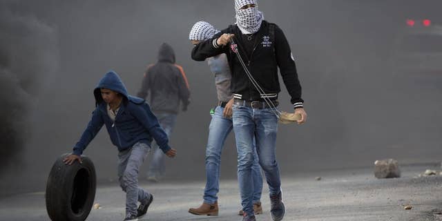 Palestinian protesters prepare to throw stones at Israeli troops Tuesday.