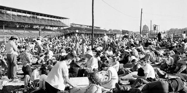 FILE - In this May 30, 1953, file photo, early arrivals at the Indianapolis Motor Speedway track lounge around on the grass in the infield of the oval Brickyard before the start of the 37th Indianapolis 500 auto race in Indianapolis, Ind. (AP Photo/File)