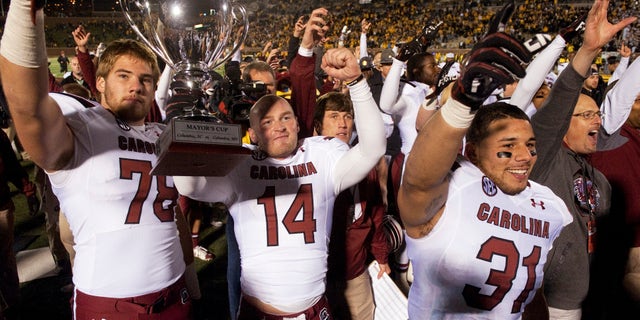 South Carolina's Connor Shaw, center, holds the Mayors Cup as he celebrates with teammates Cody Gibson, left, and Jordan Diaz, right, after the team defeated Missouri 27-24 in an NCAA college football game Saturday, Oct. 26, 2013, in Columbia, Mo. (AP Photo/L.G. Patterson)