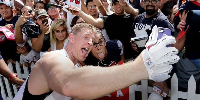 Houston Texans defensive end J.J. Watt, left, takes a selfie with Nina Munduia after an NFL football training camp practice on Saturday, July 26, 2014, in Houston. (AP Photo/David J. Phillip)