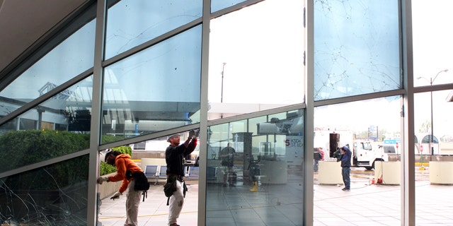 April 23: From left to right, Shaun Jones and Jacob Caldwell of BAM Contracting in St. Louis, work to repair damage to windows in the main terminal of St. Louis' Lambert International Airport