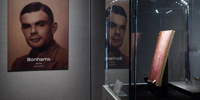 FILE - In this Thursday, March 19, 2015 file photo, a notebook of British mathematician Alan Turing is displayed in front of his portrait during an auction preview in Hong Kong. Thousands of men convicted under now-abolished anti-homosexuality laws in Britain have been pardoned posthumously under a law passed on Tuesday, Jan. 31, 2017 and many more still alive can now apply to have their criminal convictions wiped out. Calls for a general pardon have noted the 1954 suicide of World War II codebreaking hero Alan Turing after his conviction for "gross indecency." After he received a posthumous royal pardon in 2013, pressure for pardons intensified. (AP Photo/Kin Cheung, file)