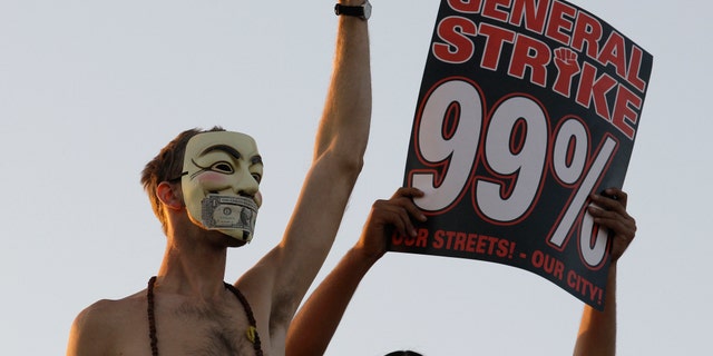 FILE — In this Nov. 2, 2011 photo, Occupy Wall Street protestors stand on top of a parked semi truck during a march from downtown Oakland, Calif., to the port of Oakland. From New York to San Francisco to London, some of the demonstrators decrying a variety of society's ills are sporting stylized masks loosely modeled on a 17th-century English terrorist, whether they know it or not. The masks come from "V for Vendetta," a comic-based movie whose violent, anarchist antihero fashions himself as a modern Guy Fawkes, the Catholic insurrectionist executed four centuries ago for trying to blow up Parliament. (AP Photo/Jeff Chiu)