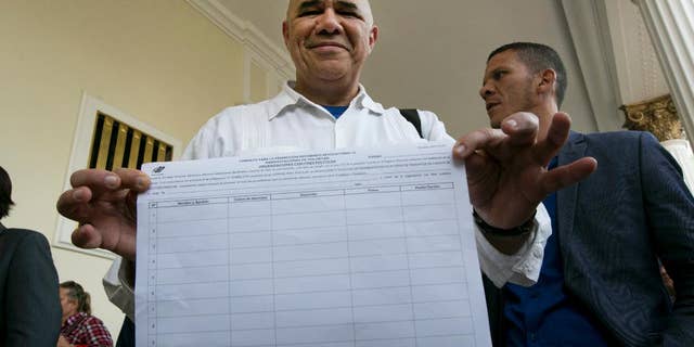 Jose Torrealba executive secretary of Venezuela's opposition coalition, Mesa de la Unidad Democratica, MUD, shows one of the petition sheets needed to collect around 200,000 signatures to allow MUD to try and initiate a recall referendum against President Nicolas Maduro, at the National Assembly building in Caracas, Venezuela, Tuesday, April 26, 2016. Although Maduro's approval rating has plummeted amid spiraling triple-digit inflation, a deep recession and widespread shortages, booting him from office won't be easy. (AP Photo/Ariana Cubillos)