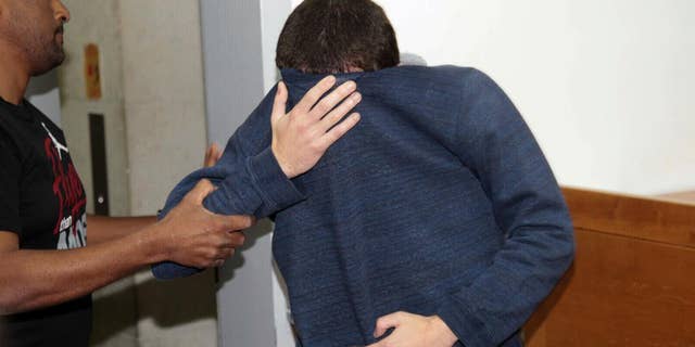 The suspect covering his face in court.