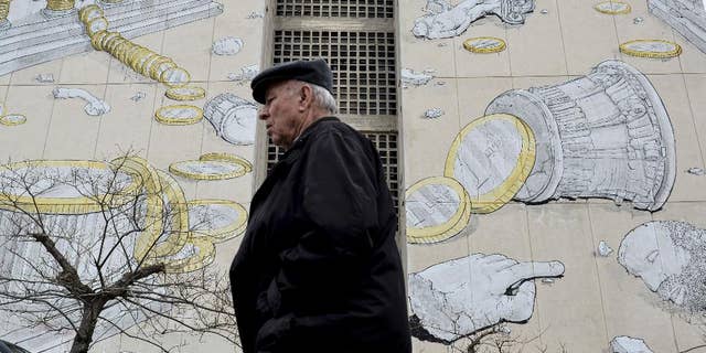 A man walks past a mural in the northern Greek town of Thessaloniki, on Wednesday, March 11, 2015. Greece is quickly running out of cash and has to repay debts this month to the International Monetary Fund — which co-funded Greece's 240 billion euro bailout — as well having as treasury bills coming due. (AP Photo/Giannis Papanikos)