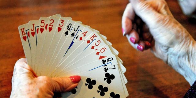 FILE - In this April 10, 2014, file photo, a card player studies her hand during a bridge game at a restaurant in St. Paul, Minn. Research published on Monday, Jan. 30, 2017, shows that even in one's 70s and beyond, simple activities including web-surfing, playing bridge and socializing can stave off mental decline. (Jean Pieri/Pioneer Press via AP)