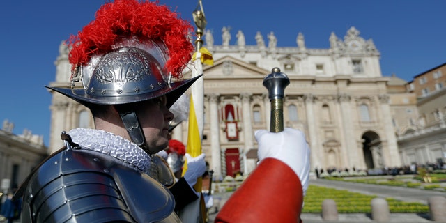 Vatican Swiss Guards stand at attention in front of St. Peter's Basilica prior to the arrival of Pope Francis to celebrate Easter Mass, Sunday, April 1, 2018.