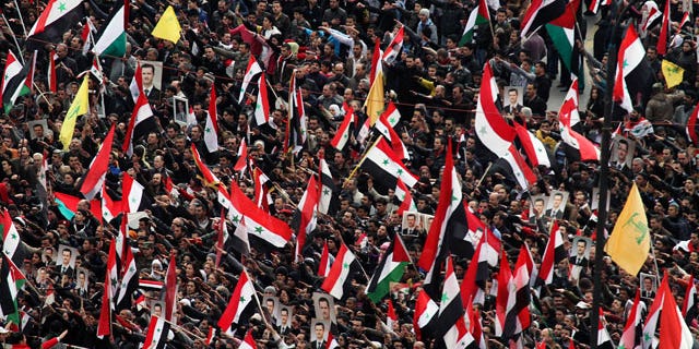 Jan. 11, 2012: Pro-Syrian regime protesters wave the national flag, as well as Hezbollah flags, in yellow, as they gather during a demonstration to show support for Syrian President Bashar Assad at a central square in Damascus, Syria.