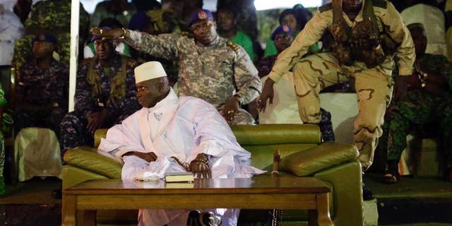 FILE- In this Tuesday Nov. 29, 2016 file photo, Gambian officers signal to the media not to block the public's view during President Yahya Jammeh's final rally in Banjul, Gambia. A Gambian court has postponed a decision on the disputed presidential election until next week. The delay of the ruling party's case until Monday, Jan. 16, 2017 sets up a collision course with the opposition, which still plans the inauguration of President-elect Adama Barrow on Jan 19. (AP Photo/Jerome Delay, File)