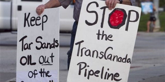 File: Sept. 21, 2010: An unidentified protester opposed to the Keystone XL pipeline carries signs, in Omaha, Neb.