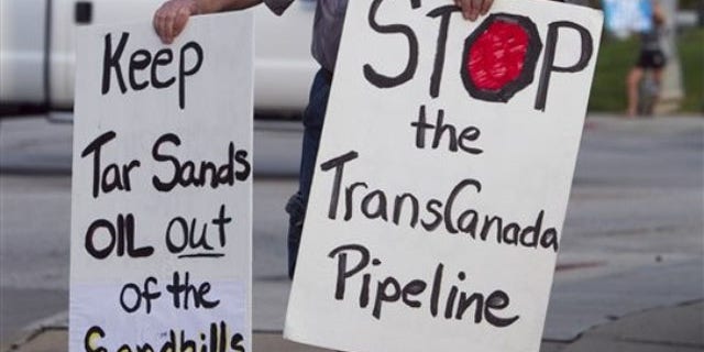 File: Sept. 21, 2010: An unidentified protester opposed to the Keystone XL pipeline carries signs, in Omaha, Neb.