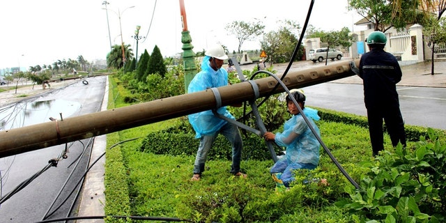 Workers repair a fallen electricity pole in the central province of Phu Yen, Vietnam, Saturday, Nov. 4, 2017.