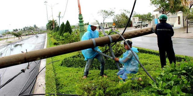 Workers repair a fallen electricity pole in the central province of Phu Yen, Vietnam, Saturday, Nov. 4, 2017.