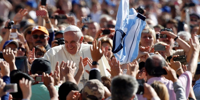 A faithful tosses in the air a jersey with the colors of the Argentine flag as Pope Francis greets faithful upon arrival for his weekly general audience in St. Peter's Square at the Vatican, Wednesday, Sept. 18, 2013. (AP Photo/Riccardo De Luca)