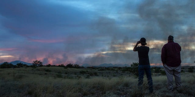 In this Monday, April 24, 2017 photo, people watch the Sawmill Fire from Las Cienegas Conservation Area north of Sonoita, Ariz.