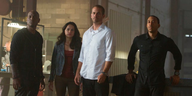This photo provided by Universal Pictures shows, from left, Tyrese Gibson as Roman, Michelle Rodriguez as Letty, Paul Walker as Brian, and Chris Ludacris as Tej, in a scene from "Furious 7." (AP Photo/Universal Pictures, Scott Garfield)