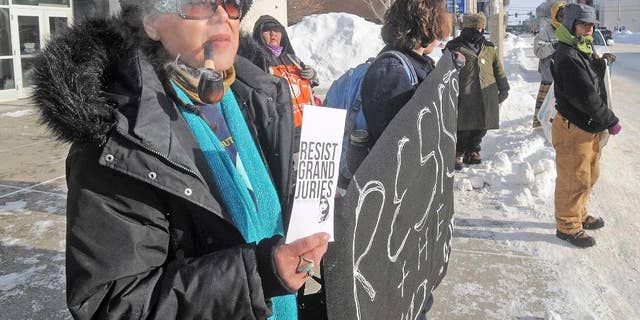Vivian Billy, left, was outside the Federal Building in downtown Bismarck on Wednesday, Jan. 4, 2017, handing out resist grand jury pamphlets while helping hold a banner with other protesters against the Dakota Access Pipeline. (Tom Stromme/The Bismarck Tribune via AP)