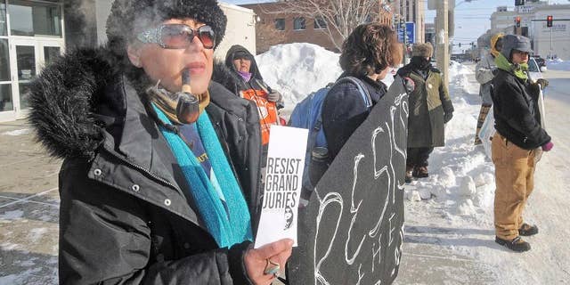 Vivian Billy, left, was outside the Federal Building in downtown Bismarck on Wednesday, Jan. 4, 2017, handing out resist grand jury pamphlets while helping hold a banner with other protesters against the Dakota Access Pipeline. (Tom Stromme/The Bismarck Tribune via AP)