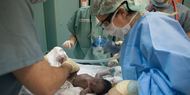 PORT-AU-PRINCE, HAITI - JANUARY 21: Doctors tend to a newborn baby girl named Esther, delivered by C-section on board the USNS Comfort, a U.S. Naval hospital ship, on January 21, 2010 in Port-au-Prince, Haiti. Esther is the first baby ever born on the ship; her mother suffered a crushed pelvis during Haiti's recent earthquake. The Comfort deployed from Baltimore with 550 medical personnel on board to treat earthquake victims and arrived in Haiti on January 20. (Photo by Brendan Hoffman/Getty Images)