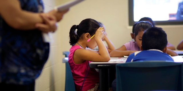 In this Wednesday, Sept. 10, 2014 photo, elementary aged children talk about a short story in Spanish during a class at the Karnes County Residential Center, a temporary home for immigrant women and children detained at the border in Karnes City, Texas. (AP Photo/Eric Gay)
