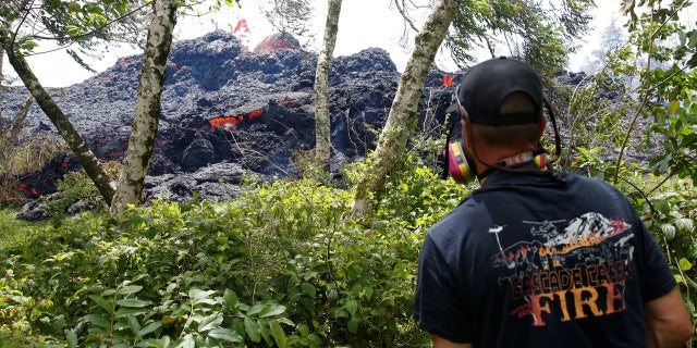 An onlooker watches as lava erupts from a fissure east of the Leilani Estates subdivision during ongoing eruptions of the Kilauea Volcano
