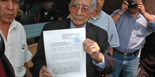 FILE - In this May 27, 2005 file photo, the former boss of Mexico's powerful oil workers union, Joaquin Hernandez Galicia, holds up a lawsuit on corruption charges he filed against the current union boss of Pemex outside a courthouse in Mexico City. Hernandez was an old-style Mexican labor leader who became one of the country's most powerful and wealthiest men through patronage, corruption and strong-arm tactics. A son of the once-feared boss says Hernandez, known as "La Quina," has died after spending several days in a hospital in the northern city of Tampico for stomach problems. He was 91. (AP Photo/Roberto Velazquez, File)