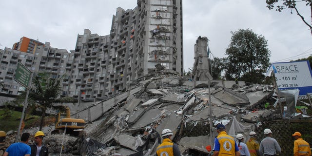 Rescue workers look at the remains of a building that collapsed late Saturday, in Medellin, Colombia, on Sunday, Oct. 13, 2013. Medellin disaster preparedness chief Jaime Enrique Gomez says they're trying to rescue 11 people missing in the collapse of a high-rise building and they still hold out hope of finding all alive following the Saturday night collapse in one of the most exclusive neighborhoods of Medellin, Colombia's second-largest city. (AP Photo/Luis Benavides)
