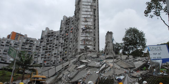Rescue workers look at the remains of a building that collapsed late Saturday, in Medellin, Colombia, on Sunday, Oct. 13, 2013. Medellin disaster preparedness chief Jaime Enrique Gomez says they're trying to rescue 11 people missing in the collapse of a high-rise building and they still hold out hope of finding all alive following the Saturday night collapse in one of the most exclusive neighborhoods of Medellin, Colombia's second-largest city. (AP Photo/Luis Benavides)