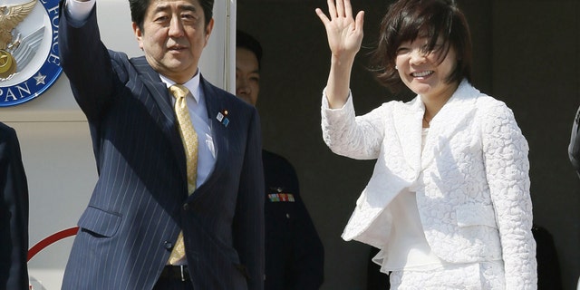 Japanese Prime Minister Shinzo Abe and his wife Akie wave before boarding a plane at Tokyo's Haneda Airport Friday, May 24, 2013. Abe is traveling to Myanmar for a three-day trip, the first visit to the country by a Japanese leader in 36 years. (AP Photo/Kyodo News) JAPAN OUT, MANDATORY CREDIT